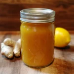 A jar of Amish "Amoxicillin" made with raw honey, garlic, ginger, and lemon, sitting on a rustic kitchen counter.