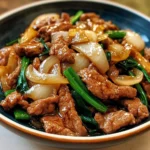 A vibrant plate of Chinese Beef and Onion Stir Fry featuring tender beef strips, caramelized onions, and garnished with green onions, served over white rice.