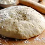 Freshly made homemade pizza dough on a floured surface, ready to roll.