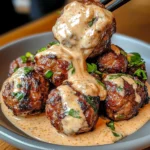 Korean BBQ meatballs glazed with a sticky sweet sauce, garnished with sesame seeds and green onions, served alongside spicy mayo dip in a white bowl.