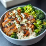 Grilled Chicken & Broccoli Bowl topped with creamy garlic sauce served over rice with lime wedges.