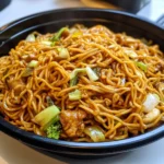 A plate of homemade Panda Express-style chow mein with fresh vegetables and green onions on top.