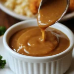 Homemade KFC-style brown gravy in a saucepan with a whisk