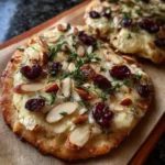 Crispy flatbread topped with brie, cranberries, almonds, and honey