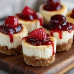 Mini cheesecakes with graham cracker crust and berry topping on a white plate