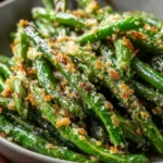 Crispy roasted green beans topped with melted Parmesan on a parchment-lined baking sheet