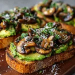 Rustic sourdough toast topped with mashed avocado and sautéed garlic mushrooms, garnished with parsley.